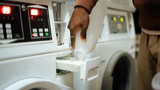 Person pouring detergent into washing machine drawer