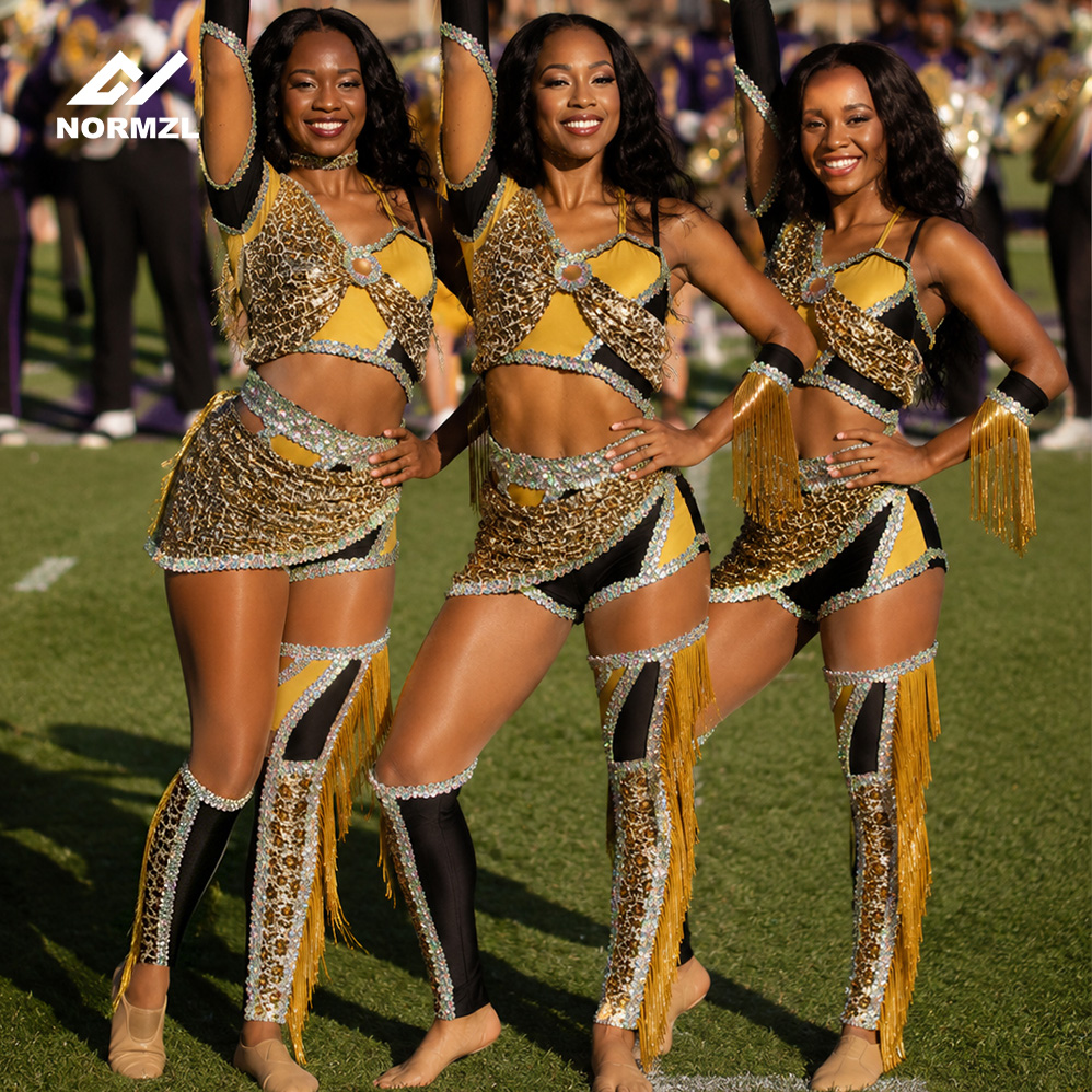 Three majorettes in gold and black uniforms posing on a football field